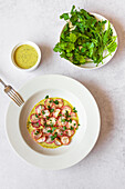 From above freshly roasted radishes served on a white plate with green tahini sauce, photographed from above.