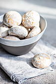 A bowl filled with fresh, powdered sugar-dusted cookies on a textured cloth