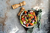 Top view of a rustic Mediterranean potato salad with spring potatoes, black olives, cherry tomatoes, spring onions, crisp lettuce, and radishes, served with a touch of elegance