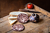 Sliced cured sausages, possibly salami, and slices of rustic bread presented on a wooden board, capturing a traditional and appetizing setup.