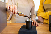 Barista pours freshly ground coffee beans into a metal filter for brewing