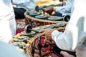 Nahaufnahme der Hände eines Unbekannten, der während einer kulturellen Zeremonie traditionelle thailändische Musikinstrumente spielt und damit die Kunst der thailändischen Musik präsentiert.