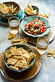 Blick von oben auf authentisches mexikanisches Pico de Gallo aus frischen Tomaten, Zwiebeln, Koriander und Zitronensaft, perfekt ergänzt durch knusprige Mais-Tortilla-Chips, serviert in handgefertigten Keramikschalen