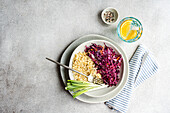 A nutritious lunch that includes a raw red cabbage and carrot salad along with a serving of bulgur Accompanied by fresh green onions, this meal is presented on a modern gray plate with a striped napkin