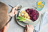 Eine Schüssel mit gesundem Essen mit einem farbenfrohen rohen Rotkohl- und Karottensalat neben flauschigem gekochtem Bulgur, serviert mit frischen grünen Zwiebeln