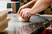 A close-up view of a person skillfully kneading pizza dough on a metallic kitchen surface, using a dough scraper