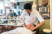 Professioneller Barbier und Haarschneider rasiert seinen Kunden im Schorem Barber Shop am Nieuwe Binnenweg, Rotterdam, Niederlande.