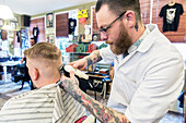 Professioneel barbier verzorgt het haar van een van zijn mannelijke klanten in de barbershop.