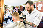 Professioneel barbier verzorgt het haar van een van zijn mannelijke klanten in de barbershop.