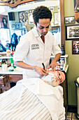 Professional Barber & Haircutter Shaving his Customer inside Schorem Barber Shop at Nieuwe Binnenweg, Rotterdam, Netherlands.