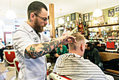 Professioneel barbier verzorgt het haar van een van zijn mannelijke klanten in de barbershop.