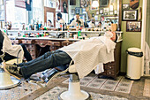 Young adult, Male Customer waiting for his Wet Schave at Schorem Barber Shop. Nieuwe Binnenweg, Rotterdam, Netherlands.