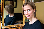 Tilburg, Netherlands. Young adult caucasian woman showing the results of a make up session, using a living room mirror.