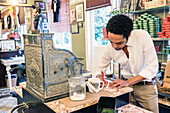 Professional Barber managing the Vintage Cash Register of Schorem Barber Shop, Nieuwe Binnenweg, Rotterdam, Netherlands.