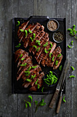 Beef flank steak on a black grill tray, refined with smoked salt and fresh spruce shoot tips