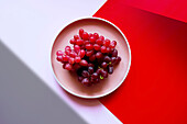 Red grapes with color blocking and geometric shadow aesthetic.