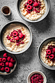 Breakfast oats and raspberry porridge in bowls on a grey background