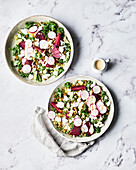 Two bowls of beetroot and kale salad on a marble slab