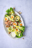 Fresh salmon caesar salad on a light blue background