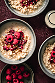 Breakfast Oatmeal porridge with raspberries on red surface