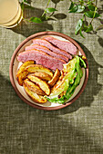 Corned beef, fried potatoes and cabbage dish on a green background