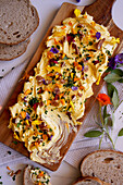 Herb, pecan and edible flowers butter board close up.