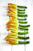 Fresh homemade courgette flowers on a white wooden background