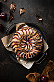 Rustic plum cake surrounded by autumn leaves and fresh fruit