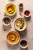 Bowls of fresh hummus with seeds, oregano, paprika