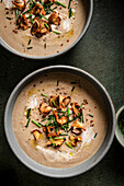 Mushroom soup bowls topped with wild mushrooms on a green surface