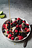 pouring honey over a berry fruit salad