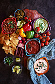 Mexican theme charcuterie board grazing platter with guacamole, salsa, beans, jalapenos, chorizo, and tortilla chips.