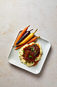 Beef Short Ribs with Mashed Potatoes and Rainbow Carrots on a Neutral Background with Soft Shadows