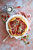 Sliced strawberry galette on a red base, decorated with icing sugar and strawberries