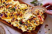 Herb, pecan and edible flowers butter board, horizontal close up.