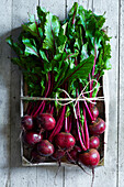 A Market box full of fresh beetroot on a gray wooden backround