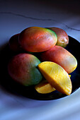 Plate of colourful mangoes, tropical summer fruits, close-up.