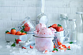 Strawberry ice cream served in a mason jar and decorated with strawberries on a light background