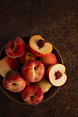 A bowl of peaches on a brown background