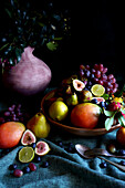 Seasonal Autumn Fruit Bowl with Apples, Pears, Mangoes, Figs, Limes, and Grapes.