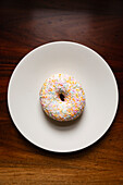 Sprinkles ring doughnut on a plate.