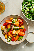 Fresh tomato salad in a bowl with yoghurt dressing on the side