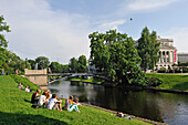 Young people on the bank of the Canal surrounding the Old Town of Riga, in front of the National Opera House, Riga, Latvia, Baltic region, Europe