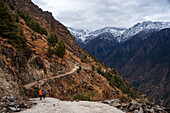 Beginn des Langtang-Tal-Treks mit Wanderern, die der Straße in Richtung der schneebedeckten Berge des Himalaya folgen, Nepal, Asien