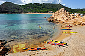 Kajakfahrer bei der Landung auf einer Insel in der Bucht Cala Pregonda bei Kap Cavalleria an der Nordküste von Menorca, Balearen, Spanien, Mittelmeer, Europa