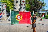 Young woman holding the Portuguese flag in Schengen European center, Schengen, Luxembourg, Europe