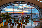 Passagiere betrachten den Sonnenuntergang in der Abflughalle des Flughafens Charles de Gaulle, Terminal 2F, Paris, Frankreich, Europa