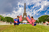 Patriotische amerikanische Frau springt und jubelt für das Team USA und die Olympischen Spiele Paris 2024 vor dem Eiffelturm, Paris, Frankreich, Europa