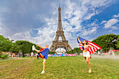 Patriotische amerikanische Frau springt und jubelt für das Team USA und die Olympischen Spiele Paris 2024 vor dem Eiffelturm, Paris, Frankreich, Europa