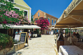 Geschäfte am Wasser und Touristen am Hafen von Fiscardo, Kefalonia, Ionische Insel, Griechische Inseln, Griechenland, Europa